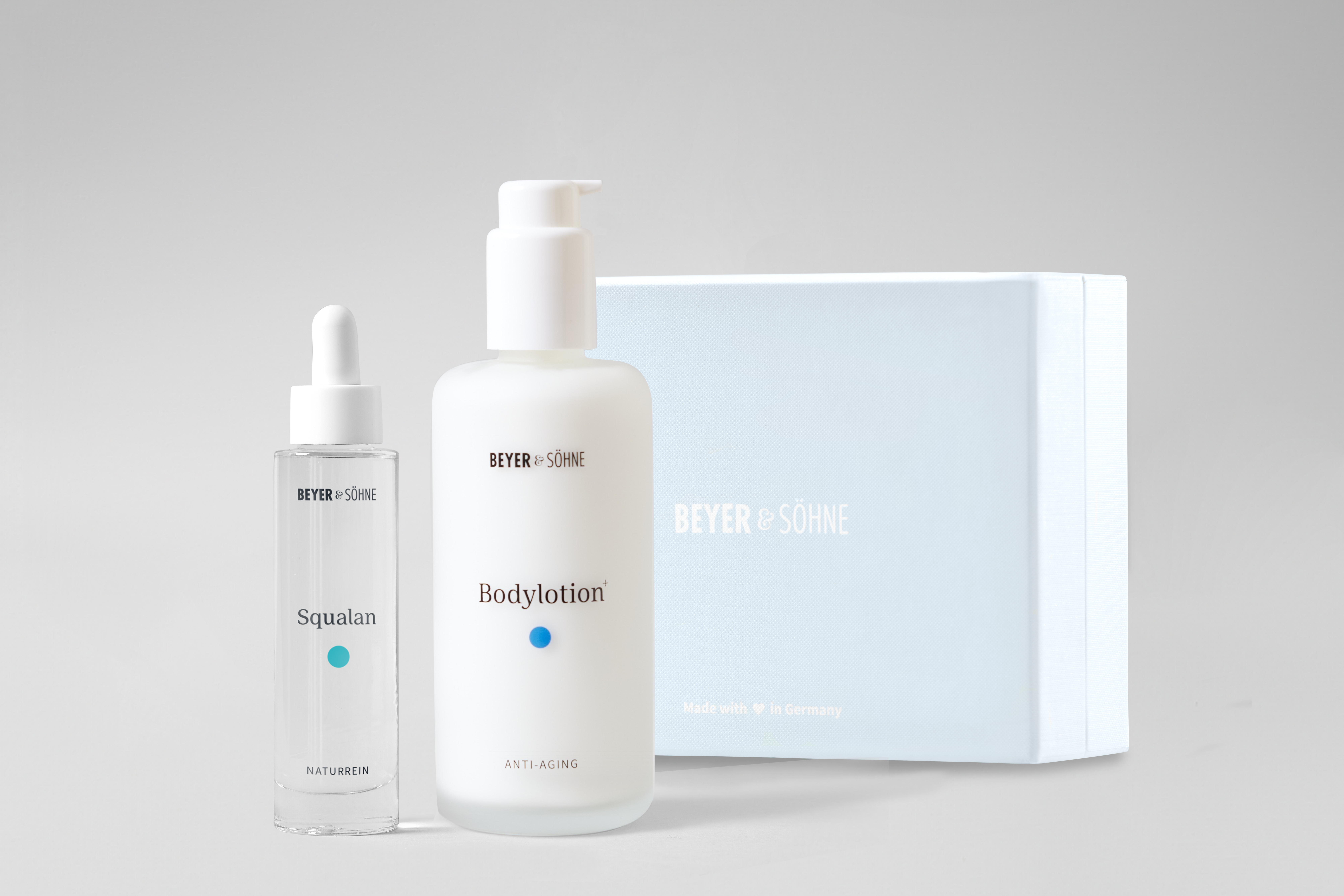 Bodylotion und Squalan in hochwertigen Glasspendern von Beyer & Söhne vor himmelblauer Geschenkbox